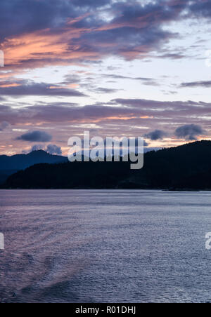 Tramonto spettacolare cielo sopra acqua e paesaggio di montagna del Marlborough Sounds in Nuova Zelanda su una tranquilla serata autunnale. Foto Stock