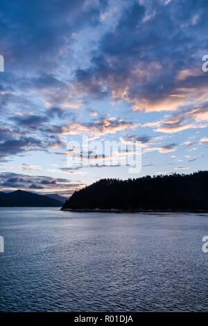 Tramonto spettacolare cielo sopra acqua e paesaggio di montagna del Marlborough Sounds in Nuova Zelanda su una tranquilla serata autunnale. Foto Stock