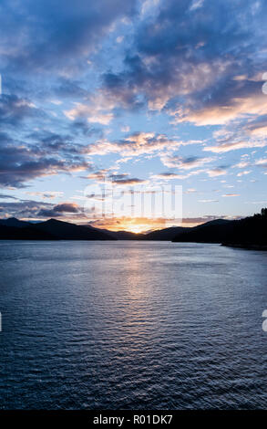 Tramonto spettacolare cielo sopra acqua e paesaggio di montagna del Marlborough Sounds in Nuova Zelanda su una tranquilla serata autunnale. Foto Stock