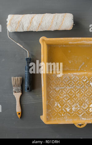 L'oggetto strumenti del lavoratore di vernice concetto, vernice spazzola a rullo e vernice bianco colore utilizzato nel vassoio di plastica. Selettiva e soft focus per lo sfondo. Foto Stock