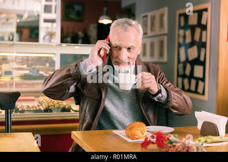 Trasmissione via IR di cura marito tenendo il suo smartphone rosso mentre la moglie di chiamata Foto Stock