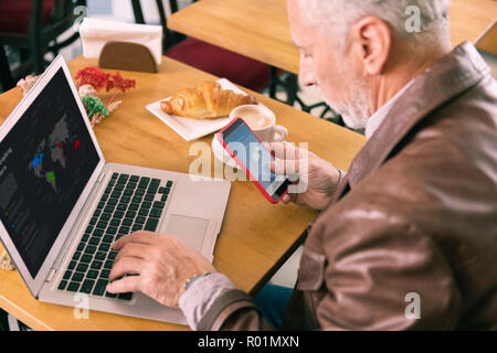 Uomo Barbuto controllo previsioni meteo sul telefono durante il fine settimana di pianificazione Foto Stock