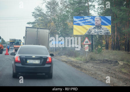 Sloviansk, Ucraina. 29 ott 2018. Cars driving passato un cartello pubblicitario per il Presidente Petro Poroshenko ("un esercito forte è una promessa di pace - Abbiamo fermato il pirata informatico e salvato il membro") sulla strada di un paese. La vita quotidiana ha restituito alla città per il popolo dopo gli scontri tra i militari ucraino e pro-russo separatisti. Credito: Gregor Fischer/dpa/Alamy Live News Foto Stock