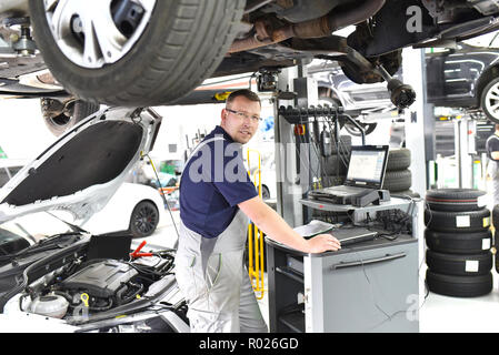 Autofficine mantiene un veicolo con la guida di un computer diagnostico - tecnologia moderna per la riparazione auto shop Foto Stock