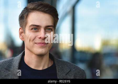 Belli alla moda uomo felice soggiorno al via in cappotto grigio e blu maglione. Foto Stock