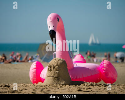 Spiaggia la scena durante le vacanze con una sabbia minion e un fenicottero gonfiabile in primo piano Foto Stock