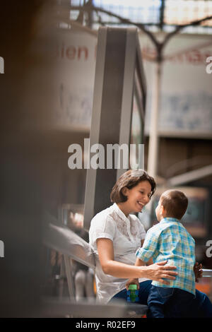 Donna seduta con il suo giovane figlio presso la stazione ferroviaria. Foto Stock