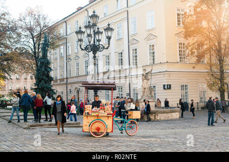 LVIV, Ucraina - Ott 31, 2018: Turisti in appoggio vicino a una fontana di Adone. Bike dolci Lviv. La piazza del mercato. Foto Stock