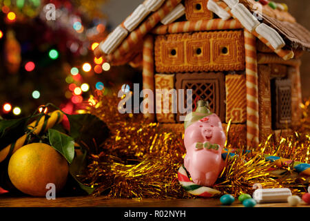 Natale maiale giocattolo sullo sfondo della casa di panpepato. Close-up. Foto Stock