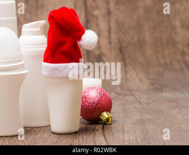 Natale skincare cosmetici. Close-up di vari prodotti cosmetici per la cura del viso e del corpo con Santa hat e palla di Natale su una superficie di legno. Copia s Foto Stock