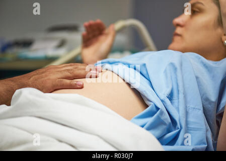 Controllo medico donna ventre vicino la vista su sfondo ospedale Foto Stock