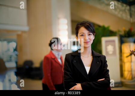 Ritratto di un giovane adulto business donna in piedi in una lobby. Foto Stock