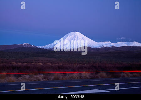 Mt Ngauruhoe all'alba, e le luci di coda sulla strada del deserto, parco nazionale di Tongariro, altopiano centrale, Isola del nord, Nuova Zelanda Foto Stock