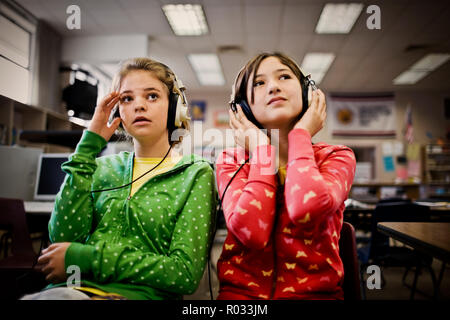 Due ragazze adolescenti seduti con le cuffie in una scuola. Foto Stock