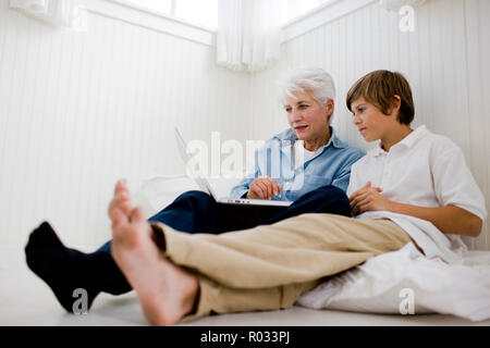 Senior donna che guarda un notebook con il suo nipote. Foto Stock