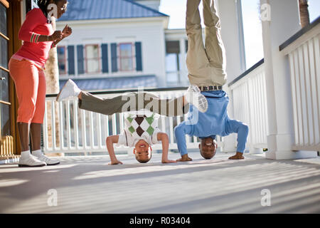 Padre e figlio breakdance sul ponte con la madre a guardare Foto Stock