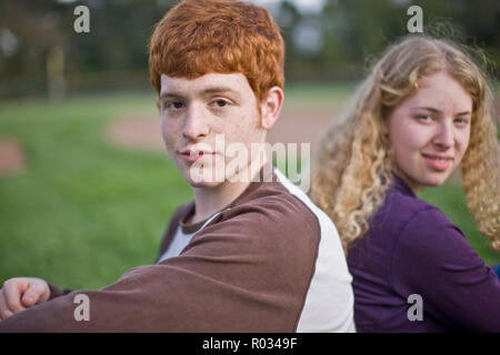 L uomo e la donna seduta su un campo sportivo, sorridente verso la telecamera Foto Stock