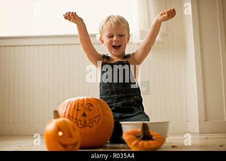 Esce da ragazzino tenendo premuto fino interiora scooped da zucche di Halloween Foto Stock