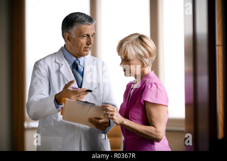 Gentile Dottore senior a conversare con un maturo paziente. Foto Stock