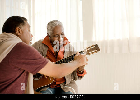 Felice l'uomo senior insegnamento sua moglie come suonare la chitarra. Foto Stock