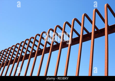 Dettaglio della recinzione piegata con aste metalliche contro un cielo blu Foto Stock