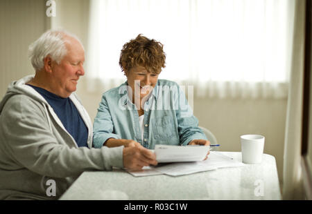 Coppia senior guardando oltre i documenti importanti. Foto Stock