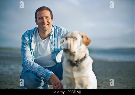 Ritratto di un uomo sorridente e il suo cane su una spiaggia. Foto Stock