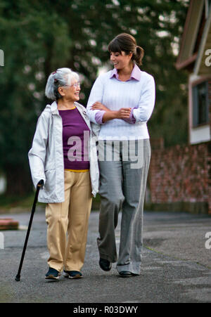 Donna anziana camminare a braccetto con il suo medico. Foto Stock