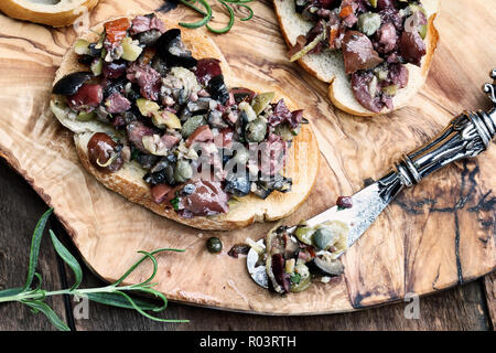 In casa oliva mescolato Tapenade fatta con aglio, capperi, olio d'oliva, Kalamata, olive nere e verdi sparsi su fette di pane abbrustolito. Immagine ripresa da overhea Foto Stock