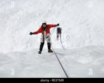 Montagna maschio ice climber rapelling off una ripida e lunga cascata ghiacciata nelle Alpi Svizzere nel profondo inverno non felice con problemi che egli ha con la CLI Foto Stock