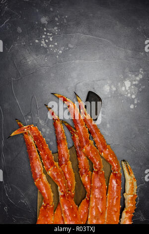 Freschi e saporiti re kamchatka crab's claw con a bordo di legno su sfondo nero Foto Stock