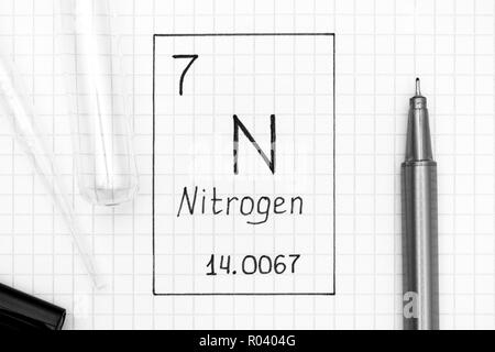 Tavola periodica degli elementi. La grafia elemento chimico azoto N con la penna nera, tubo di prova e la pipetta. Close-up. Foto Stock