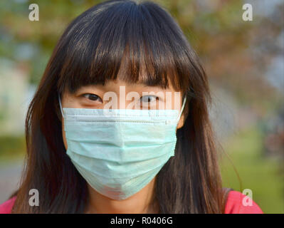 Giovane donna di Taiwan con bellissimi occhi orientali indossa una luce verde chirurgico monouso maschera facciale. Foto Stock