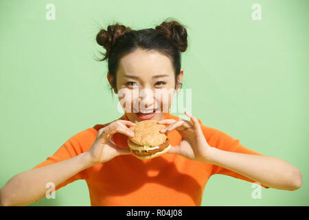 Giovani donne mangiare hamburger Foto Stock