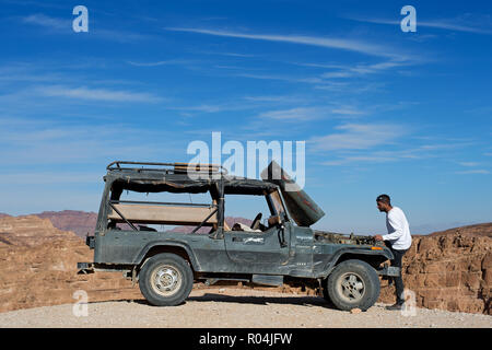 Uomo che cerca di riparare il suo carrello nel canyon colorato. Nuweiba. Egitto Foto Stock