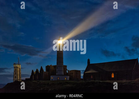 Chiesa mistica e il faro acceso oltre il cielo nuvoloso a Saint Mathieu punto, Brittany, Francia Foto Stock