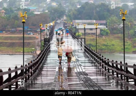 Woman Dancing sotto la pioggia caduta sul Mon ponte di legno di Sangklaburi, Thailandia Foto Stock