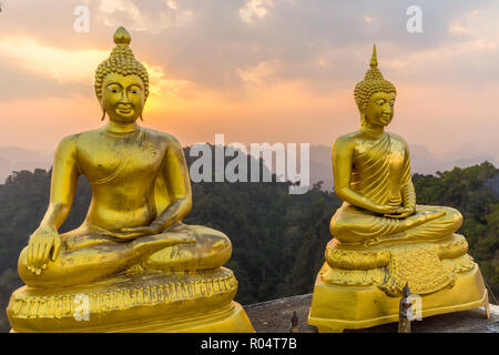 Due statua del Buddha sulla cima della montagna sotto il tramonto, Krabi tiger tempio nella grotta, Thailandia Foto Stock