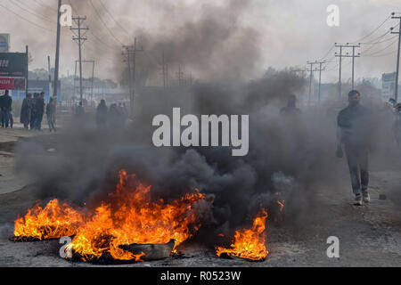 Un uomo del Kashmir vedere a piedi verso bruciando pneumatici durante gli scontri.I funzionari dicono due ribelli sono stati uccisi in una pistola la battaglia con il governo indiano le forze, scontri scoppiati in Pampore area di Pulwama alcuni 20km dalla capitale estiva di Srinagar dopo la notizia si diffuse in tutta la zona. Credito: SOPA Immagini/ZUMA filo/Alamy Live News Foto Stock