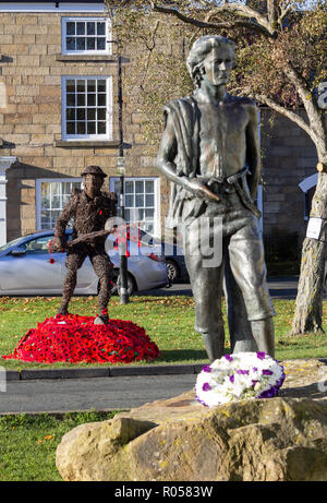 Grande Ayton village,il North York Moors National Park, North Yorkshire, Inghilterra, Regno Unito. Il 2 novembre 2018. Papaveri maglia attorno a Willow scultura della Prima Guerra Mondiale soldato in ottima Ayton village, North Yorkshire su un chiaro e gelido mattino. La scultura è in ricordo per gli uomini e le donne del villaggio che ha servito durante la Grande Guerra. Spegnere il 260 che se ne sono andati alla guerra, solo 50 restituiti. Grande Ayton era la casa d'infanzia di capitano James Cook. Scultura in primo piano è un giovane James Cook. Credito: ALAN DAWSON/Alamy Live News Foto Stock