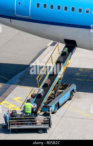 Airport Baggage handler immissione bagagli su un nastro trasportatore per l'aeromobile. Foto Stock