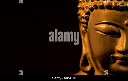 Golden BUDDA STATUETTA in atto di meditare (su sfondo nero con copia spazio) Foto Stock