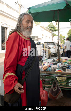 Colombiano di vecchio uomo vestito stile medievale e la vendita di prodotti di consumo quotidiano dal suo carrello nel centro cittadino di Santa Marta, Colombia. Sep 2018 Foto Stock