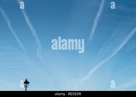 Un frammento di una lanterna su un cielo blu con le scie di condensazione Foto Stock