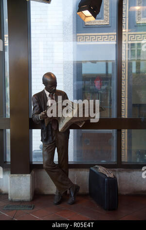 DETROIT, Michigan, Stati Uniti - Maggio 22nd, 2018: una statua di un uomo che legge un giornale su una piattaforma di Detroit il People Mover tram Foto Stock