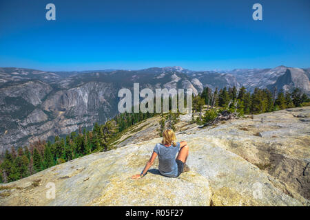 Escursionismo donna seduta rilassante a cupola Sentinel vetta del Parco Nazionale di Yosemite. Felice dopo escursioni e godendo di El Capitan vista in Sentinel Dome. Estate vacanze viaggi in California, Stati Uniti. Foto Stock