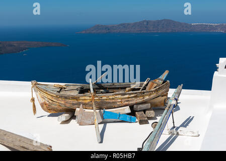 Vecchio rotto in legno barca sul tetto di casa, situata a Santorini Island, Grecia Foto Stock