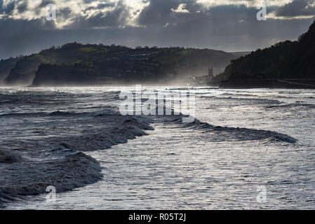 Sea Spray evidenziata dalla retroilluminazione. Teignmouth, Devon, Regno Unito e la costa in direzione sud verso Torbay. Foto Stock