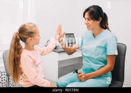 Medico scuotendo leggermente la mano della bambina in office Foto Stock