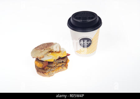 McDonald's Triple Stack uovo sandwich mcmuffin w/2 polpette di salsiccia 2 strisce di bacon 2 fette di formaggio americano sui muffin inglese con il morso prese & caffè Foto Stock